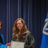 Provost Mili presents certificate to woman on stage